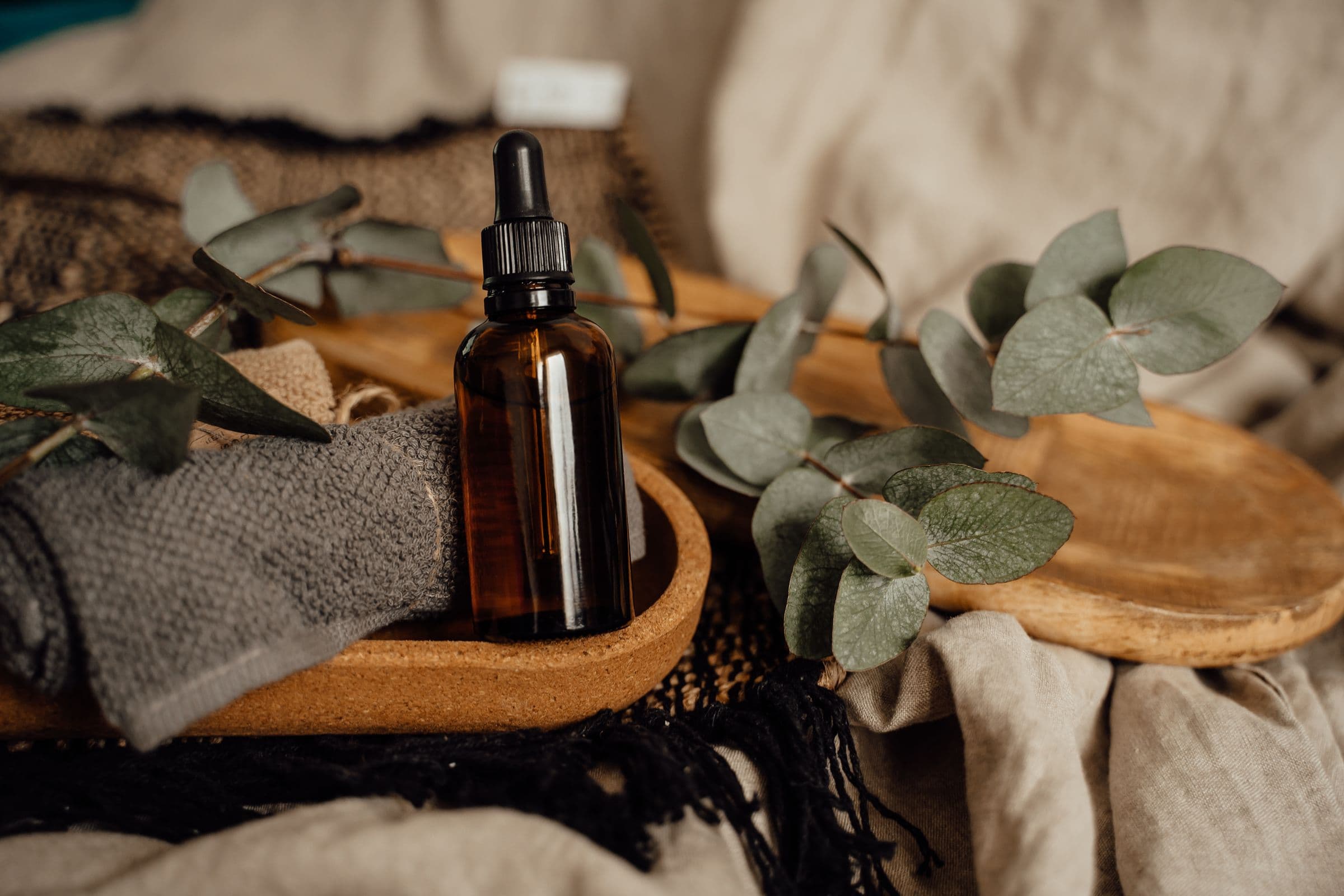 Massage oil and folded towels on a wooden tray