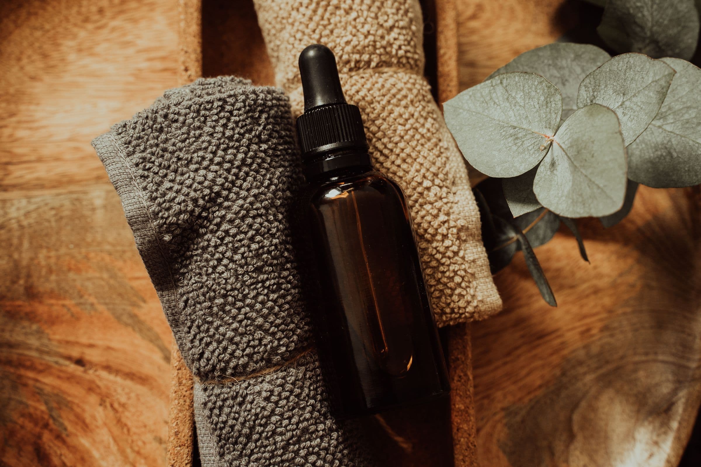 Massage oil and folded linen on a wooden surface